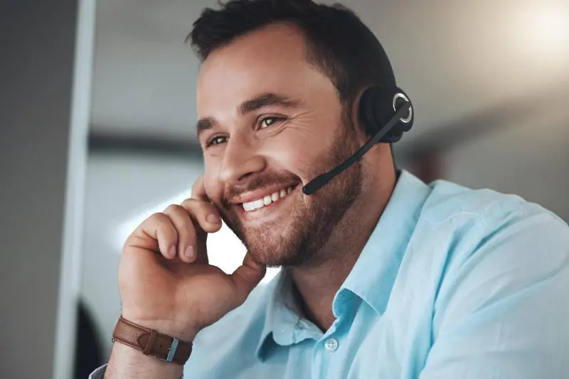 A man wearing a blue shirt has a head set on. Elevated Networks provides help desk support.